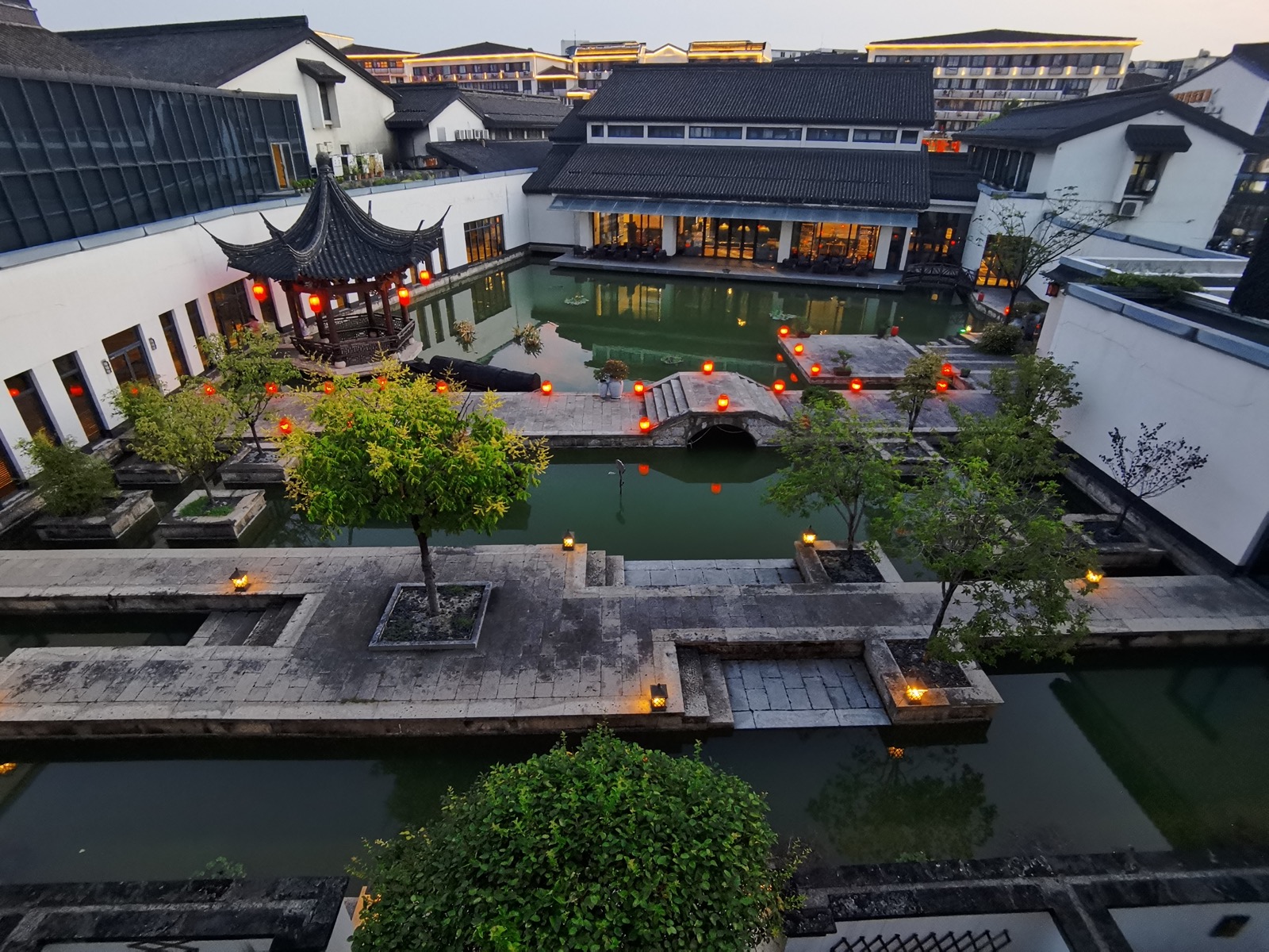 Xianheng Hotel courtyard at dusk, Shaoxing — red lanterns, pavilion, canal